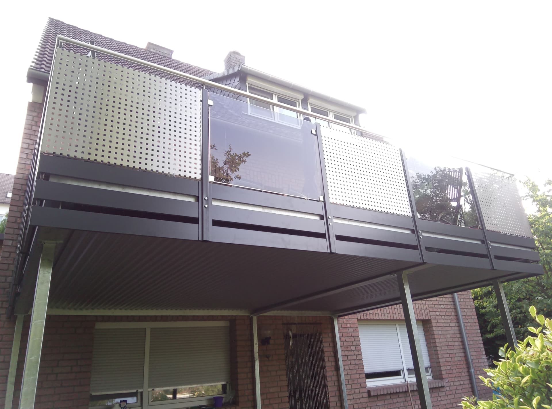 Balkon mit Lochblech- und Glasfüllung über einem Carport