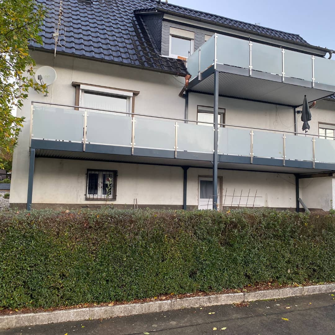 Zwei Balkone mit satinierten Glasfüllungen an einem Mehrfamilienhaus