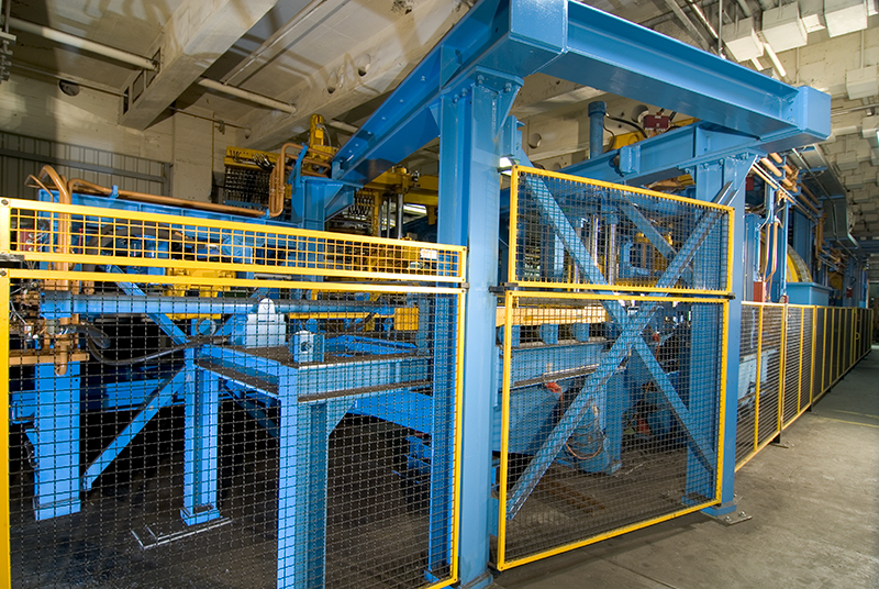 Blaue Schutzgitteranlage mit gelben Sicherheitsrahmen in einer Produktionshalle