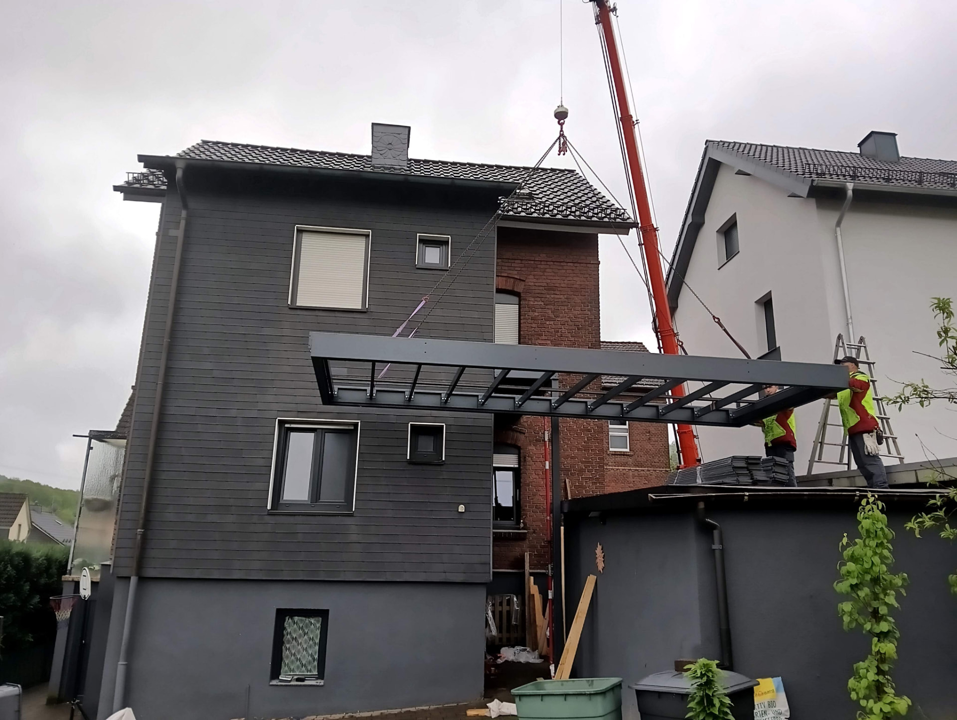 Einheben einer Terrassenüberdachung aus Stahl mit Glasdach