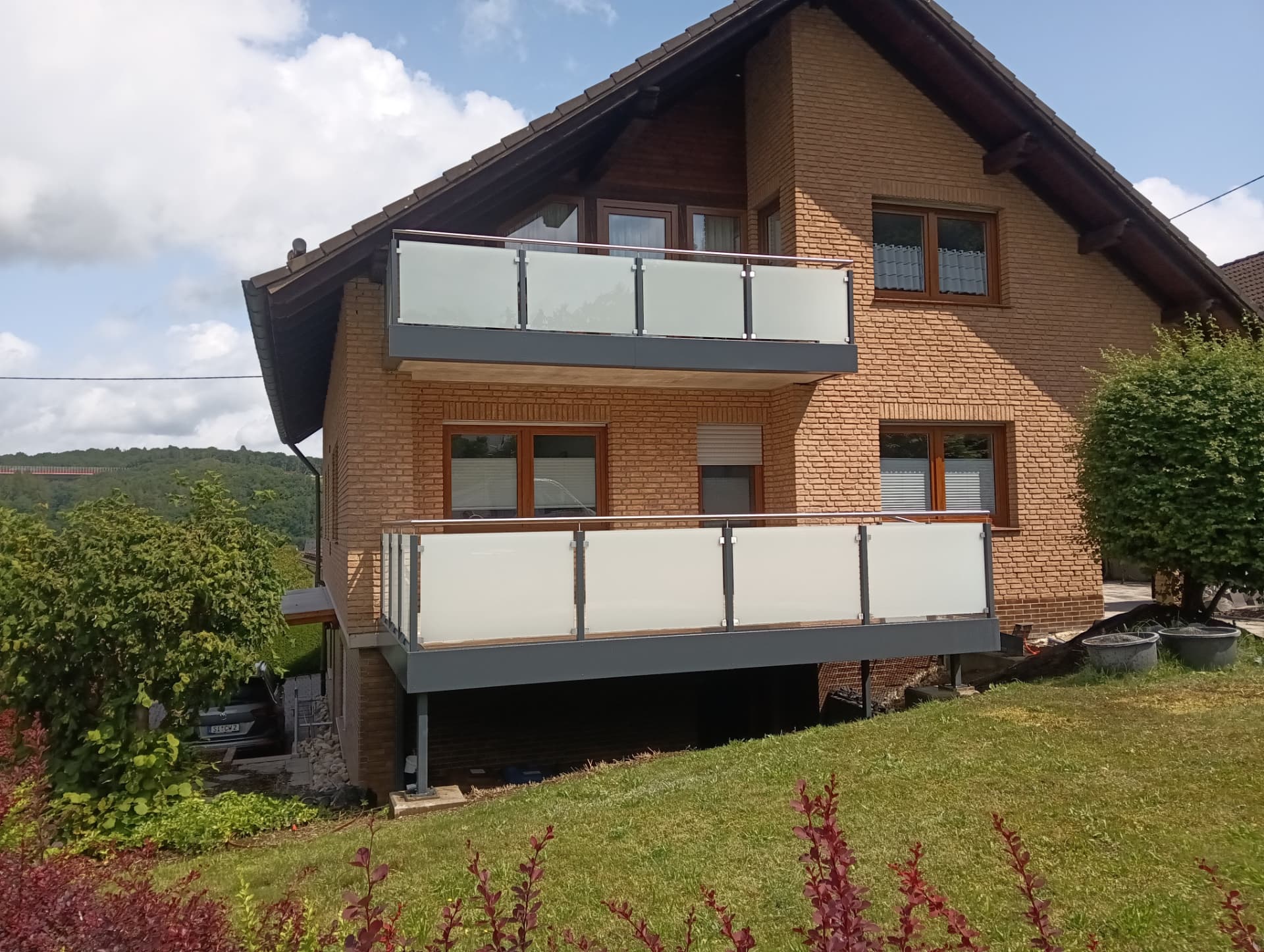 Zwei Balkone mit Glasgeländern an einem Klinkerhaus