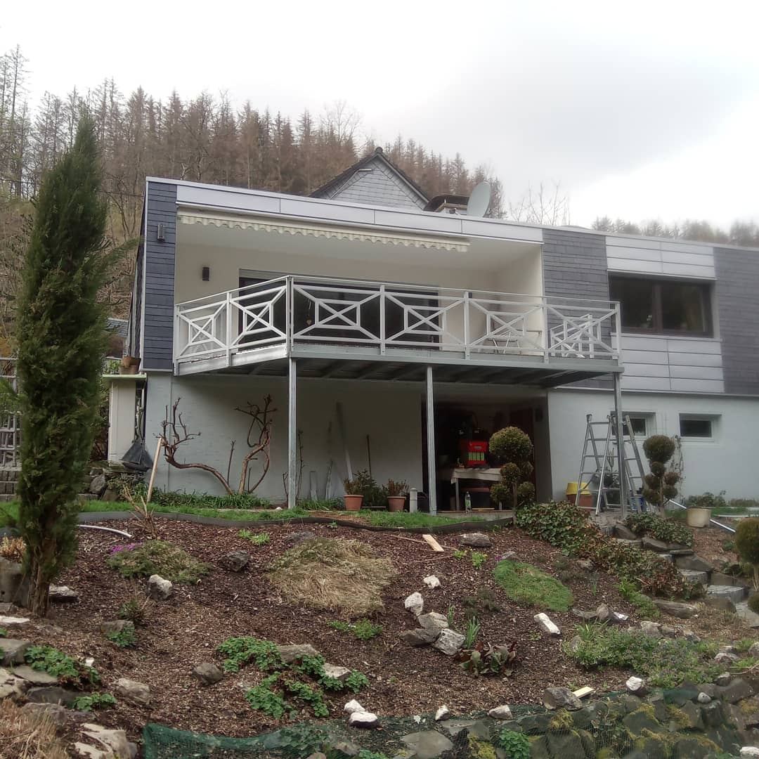 Weißes Balkongeländer mit Kreuzmuster an einem Wohnhaus